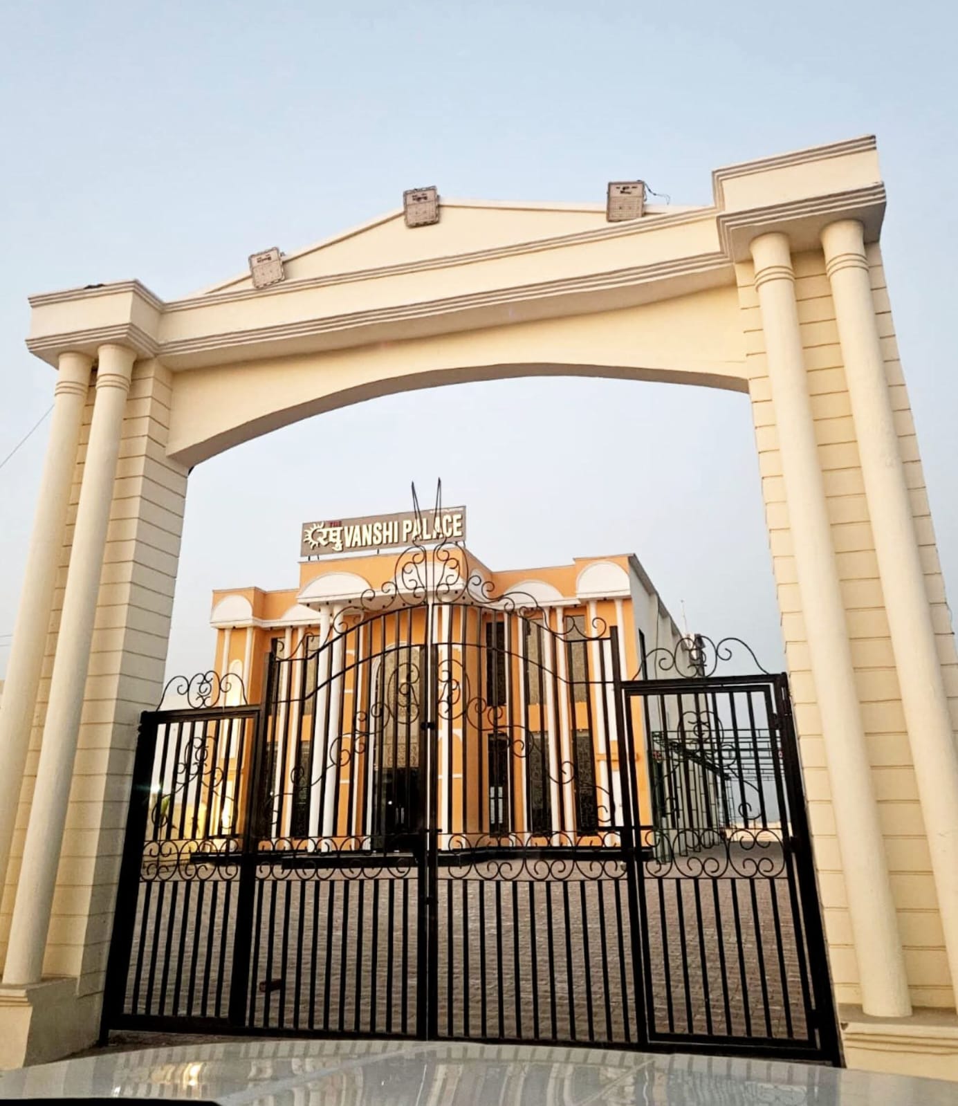 Grand entrance gateway with high arched pillars and ornate wrought iron gates framing Raghuvanshi Palace