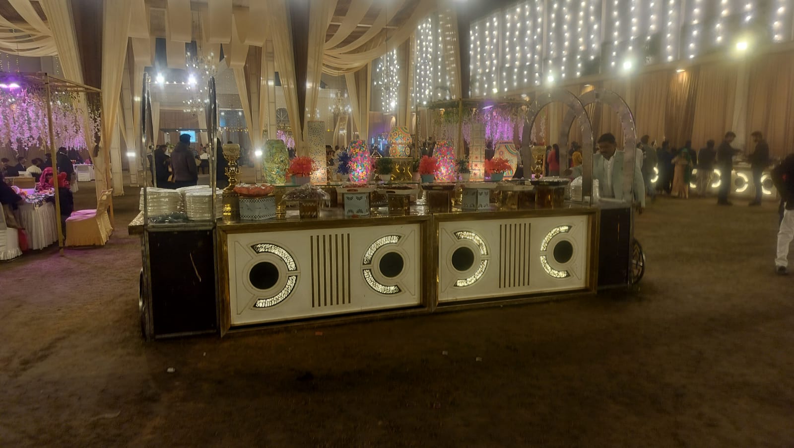 Indoor wedding catering and buffet counter setup decorated with ambient lighting panels and fairy light backdrop